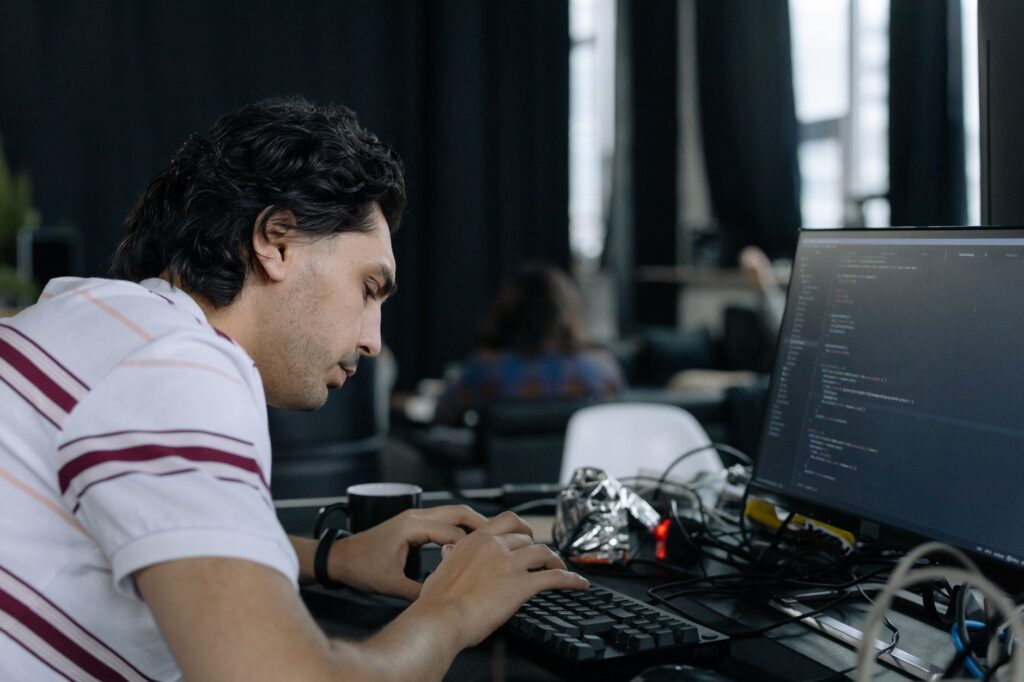 Développeur concentré devant deux écrans dans un environnement de travail moderne