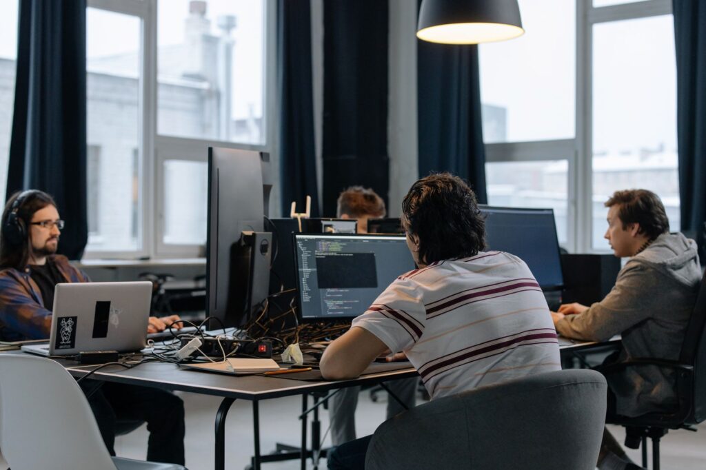 Une équipe de professionnels des TI en discussion autour d'un ordinateur portable dans un bureau moderne