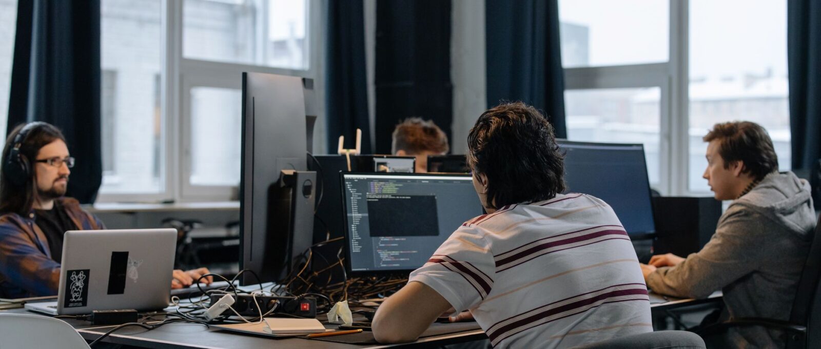 Une équipe de professionnels des TI en discussion autour d'un ordinateur portable dans un bureau moderne